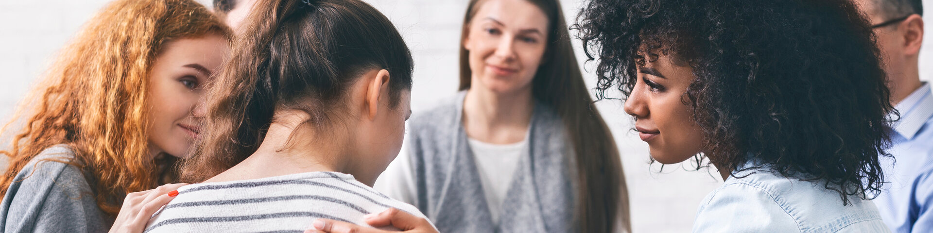 Personen, die einer Frau auf die Schulter greifen und sie mit Mitleid anschauen