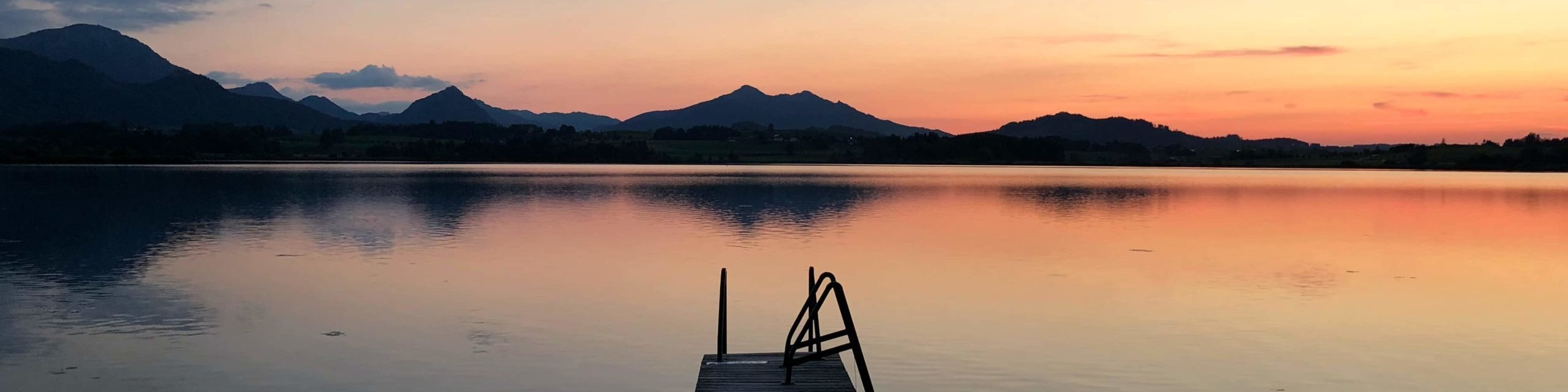 Abendstimmung: Sonnenuntergang am See mit Blick über einen Steeg