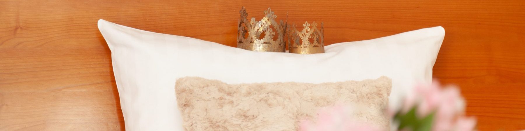 Kissen auf dem gemachten Bett mit echten, kleinen Königskrönchen für Sie und Ihn darauf