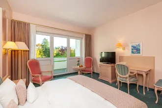 Beispielzimmer mit Bett, TV und Schreibtisch