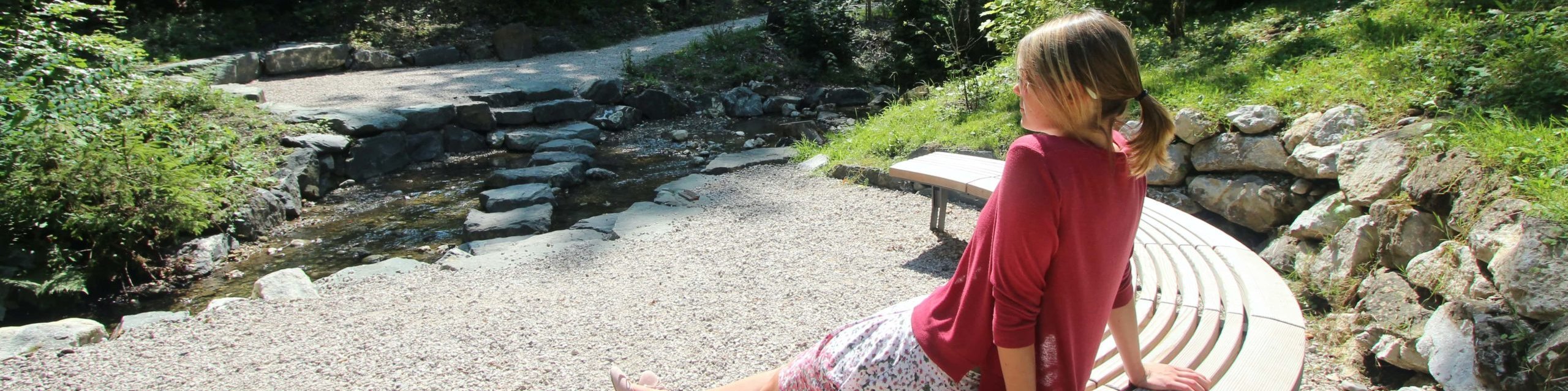 Frau beim genießen der warmen Sonne auf einer Bank am Natur-Kneipp-Becken