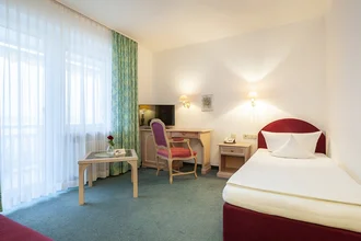 Zimmer mit Bett, TV und Schreibtischecke